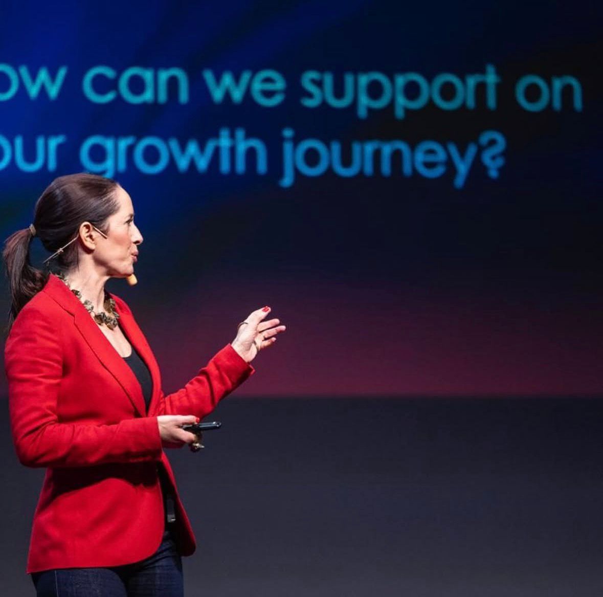 Sol Piñero Misa speaking on stage in a red jacket