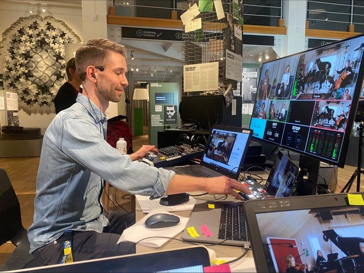 A hybrid production desk with mixing board, screens and live video feeds