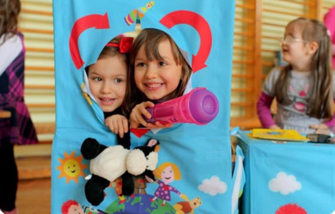 Two children smiling through a Retoy puppet theatre